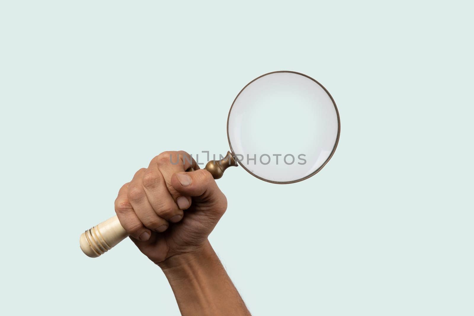 Black male hand holding a loupe or magnifying glass isolated on cyan. by TropicalNinjaStudio