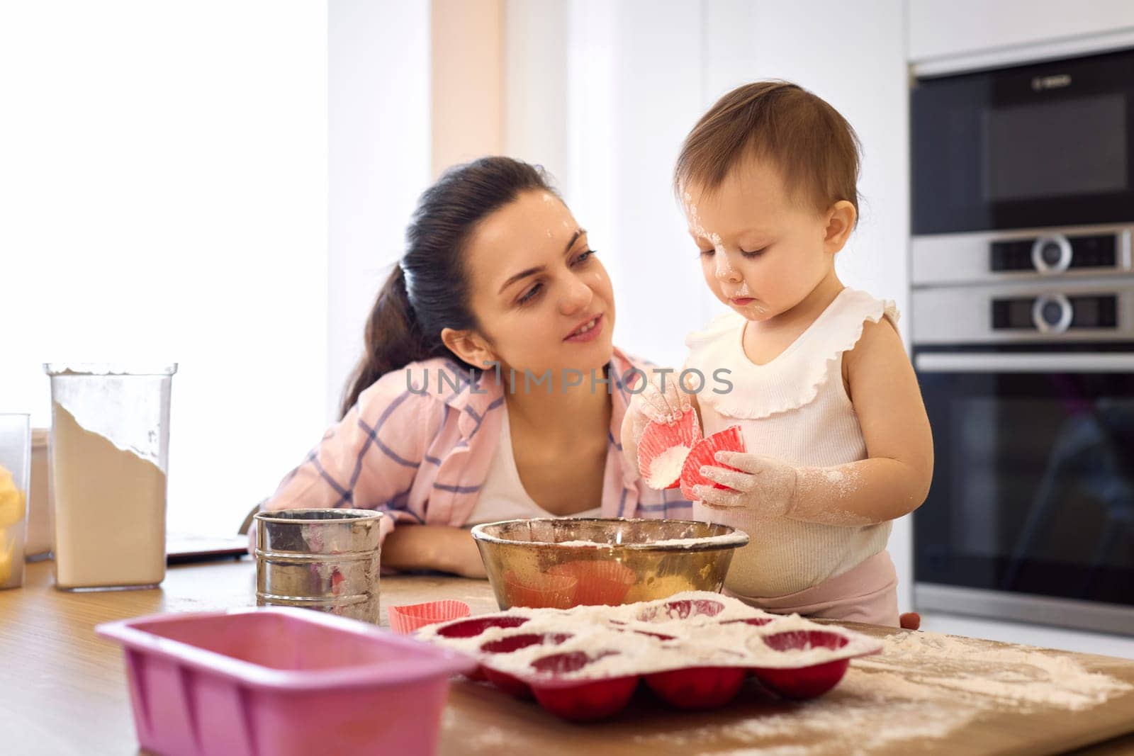 mother and little baby girl preparing the dough at the kitchen, bake cookies. happy time together