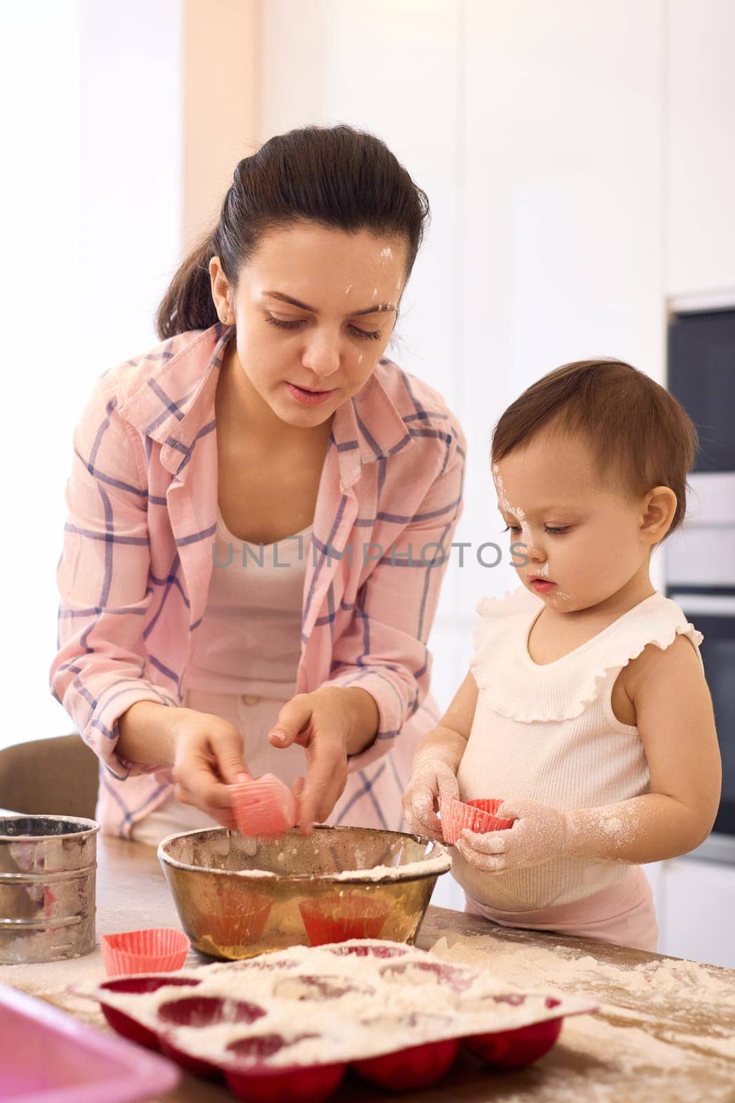 mother and little baby girl preparing the dough in the kitchen, bake cookies. happy time together