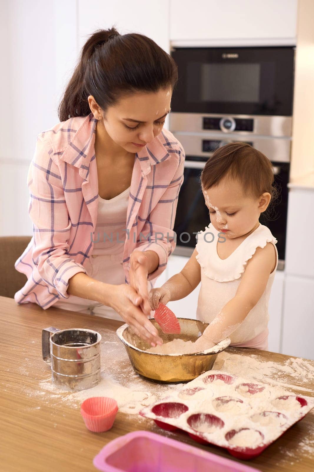 mother and little baby girl preparing the dough in the kitchen by erstudio