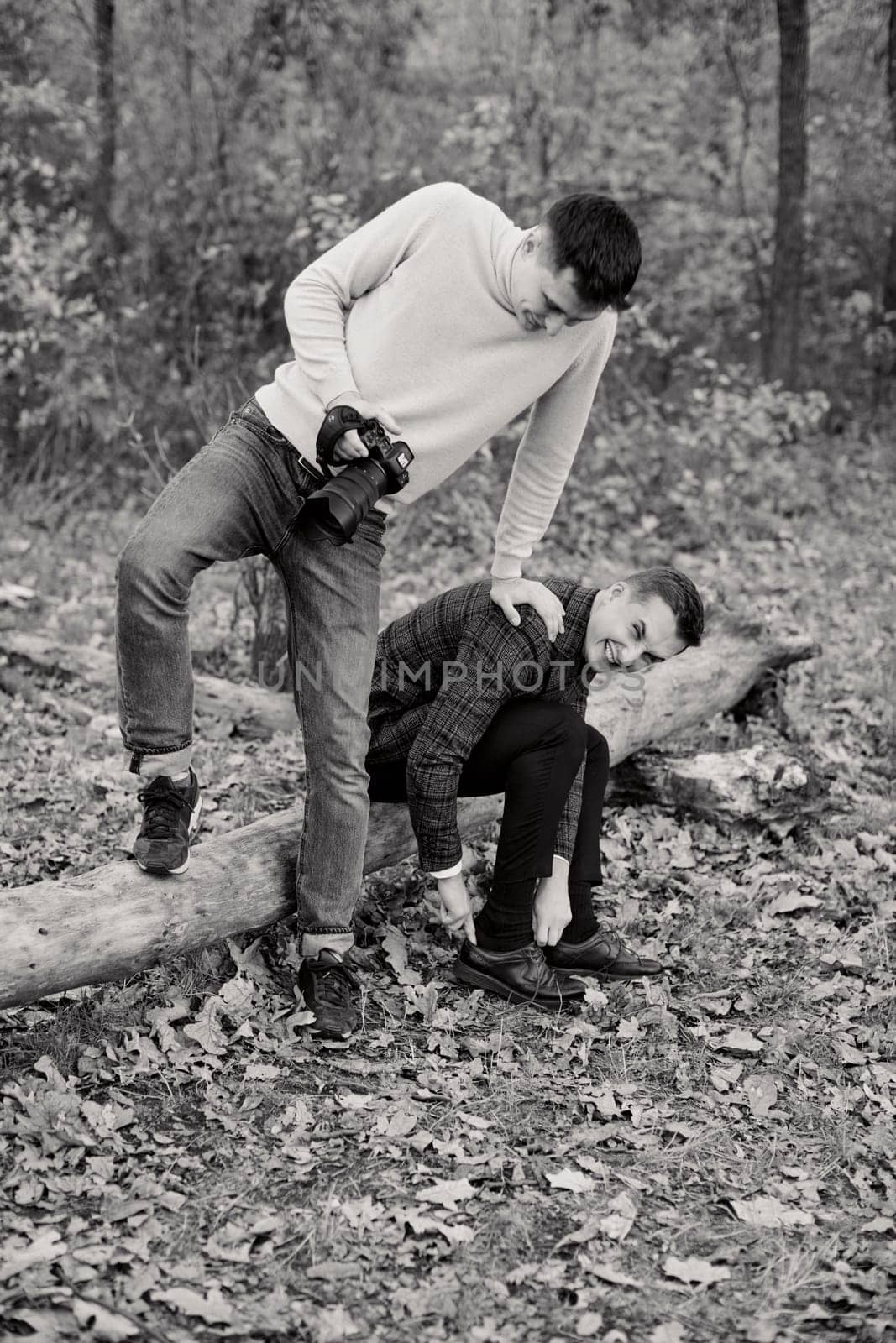 wedding photographer helps the groom put on his shoes, the guys are having fun