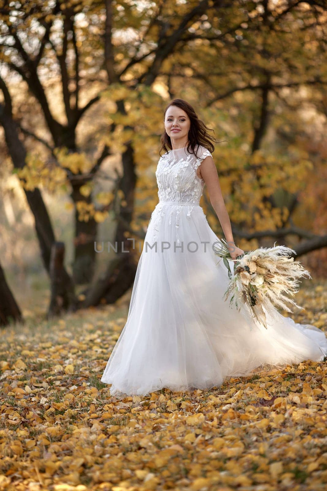 beautiful happy bride holding wedding autumn bouquet in nature