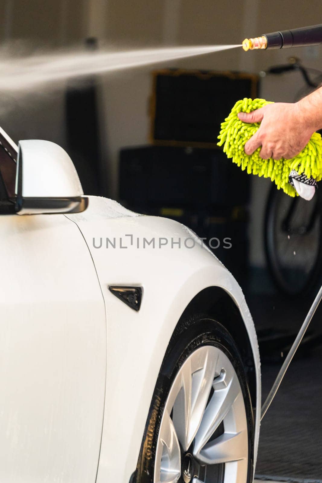 Denver, Colorado, USA-September 1, 2023-Efficiently cleaning an electric car in the comfort of a suburban driveway, combining eco-consciousness with practicality.