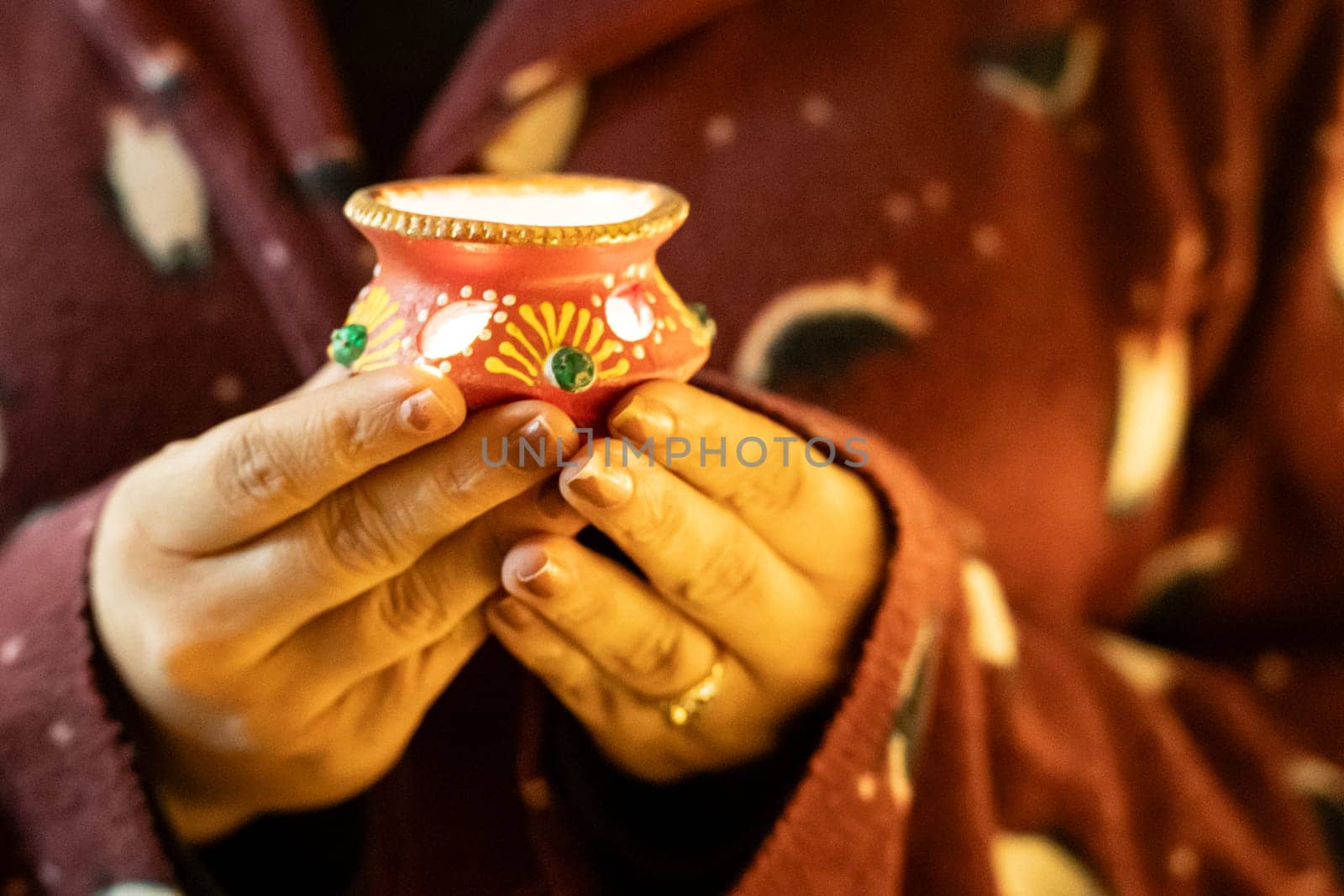 Young woman holding decorated diya looking like a earthenware pot on the eve of diwali dussera a way of bringing light on the festival by Shalinimathur