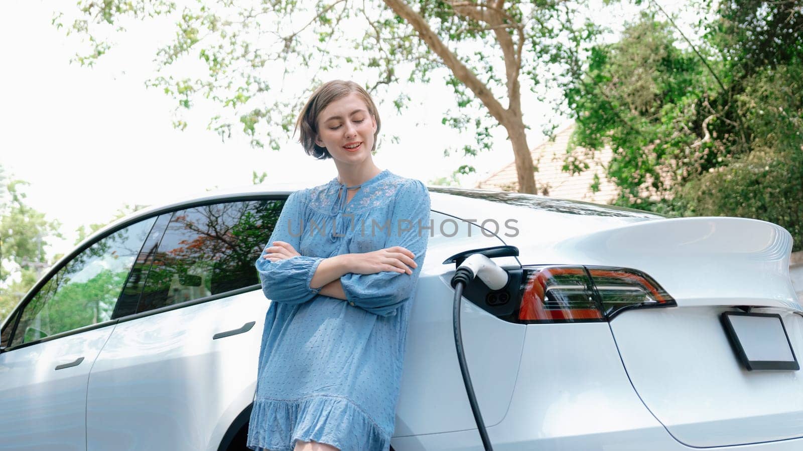 Holiday road trip vacation with beautiful young woman and EV car. Perpetual by biancoblue