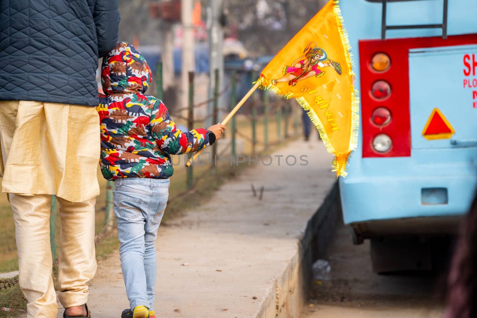 Young child face not visible carrying bhagwa saffron flag celebrating the Pran Pratishtha consecration of Ram mandir temple massive celebration in India by Shalinimathur