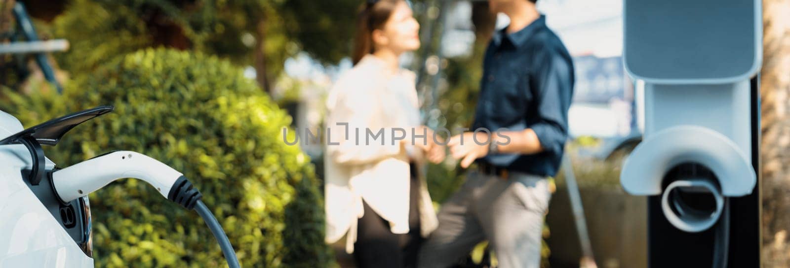 Young couple recharge electric car's battery from charging station. Expedient by biancoblue