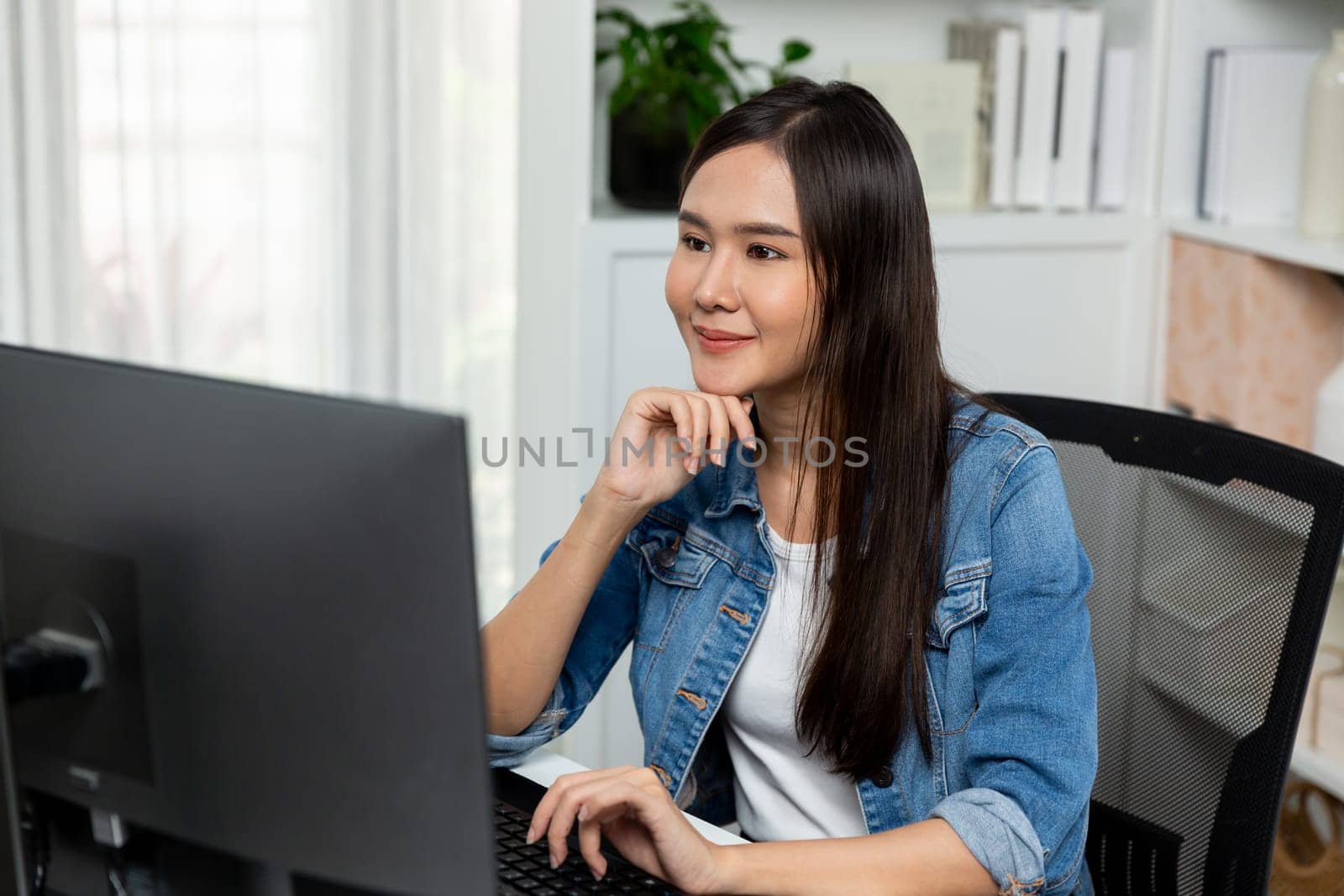 Working young beautiful asian creative manager focusing on pc, creating with new website design on new social media online channel planning with blue jeans shirt at modern home office. Stratagem.