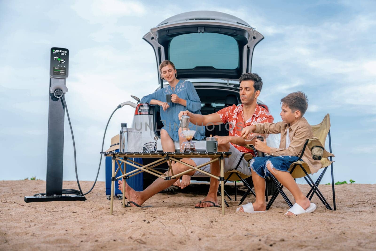 Family vacation trip traveling by the beach with electric car, happy family recharge EV car, enjoying outdoor camping coffee. Seascape travel and eco-friendly car for clean environment. Perpetual