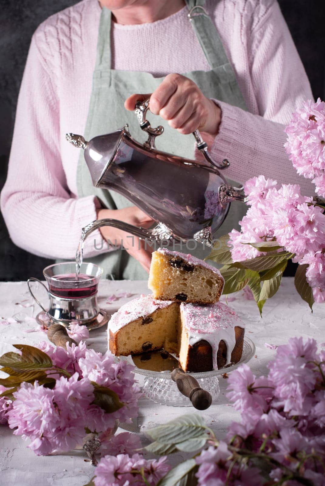 a woman pours tea from a silver teapot, background of pink sakura flowers,easter by KaterinaDalemans
