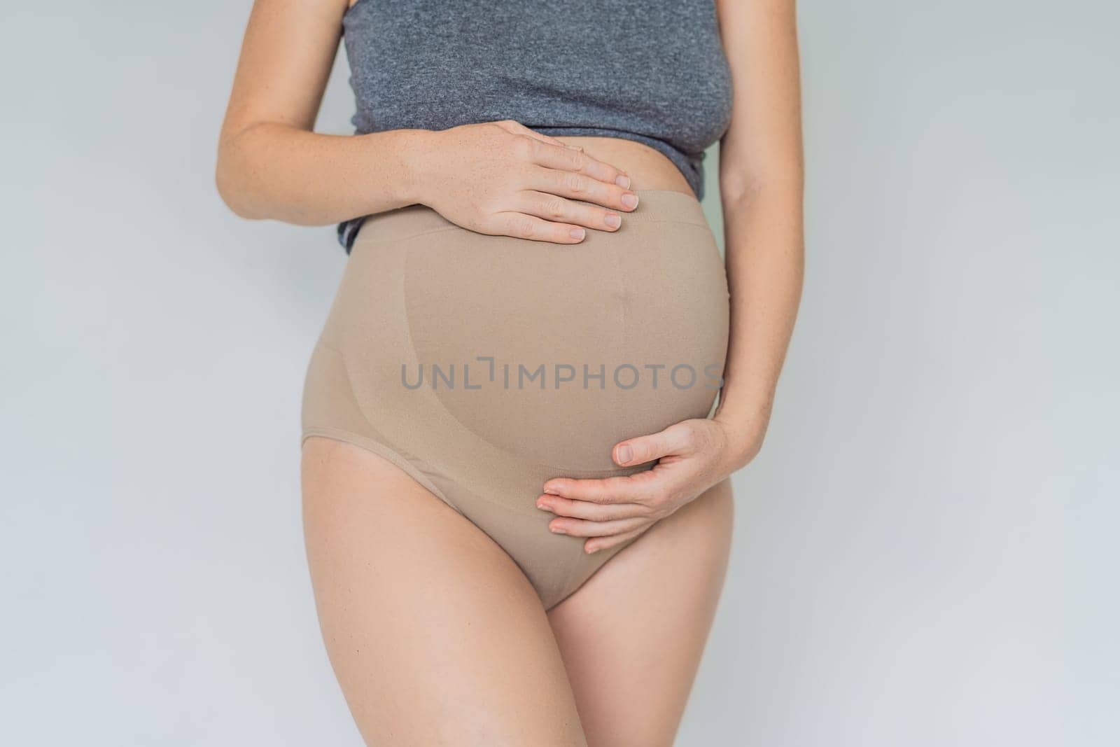 Pregnant bliss: Mom-to-be embraces her baby bump with a soft fabric bandage, providing gentle support. Maternity made comfortable by galitskaya