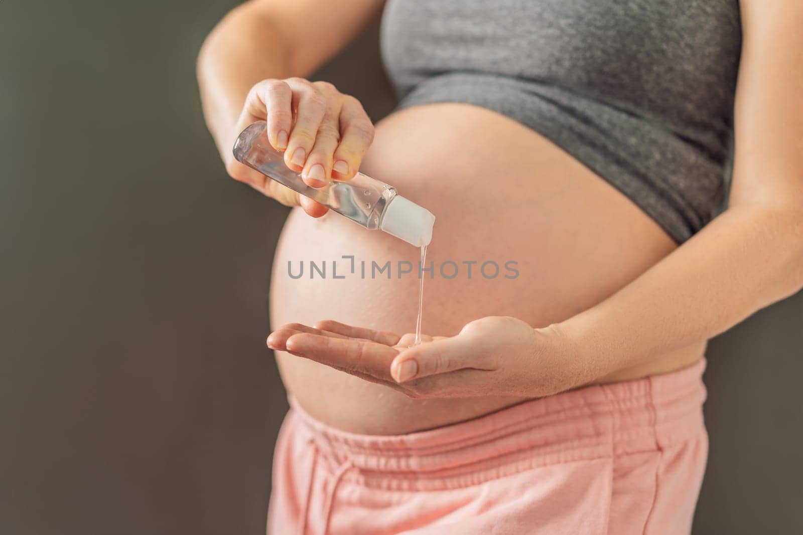 Expectant mom ensures safety, applying gel sanitizer for a clean and healthy pregnancy by galitskaya