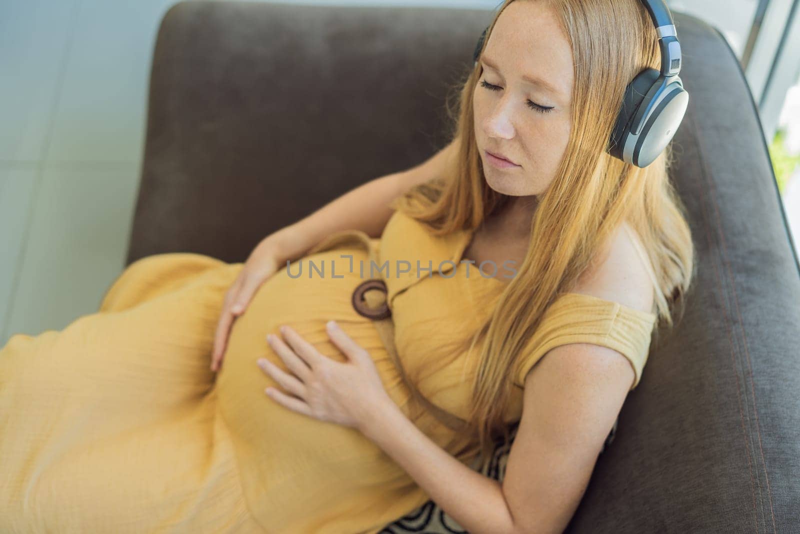 Expectant mom finds joy in her pregnancy, listening to soothing music for a serene and harmonious connection with her unborn baby by galitskaya
