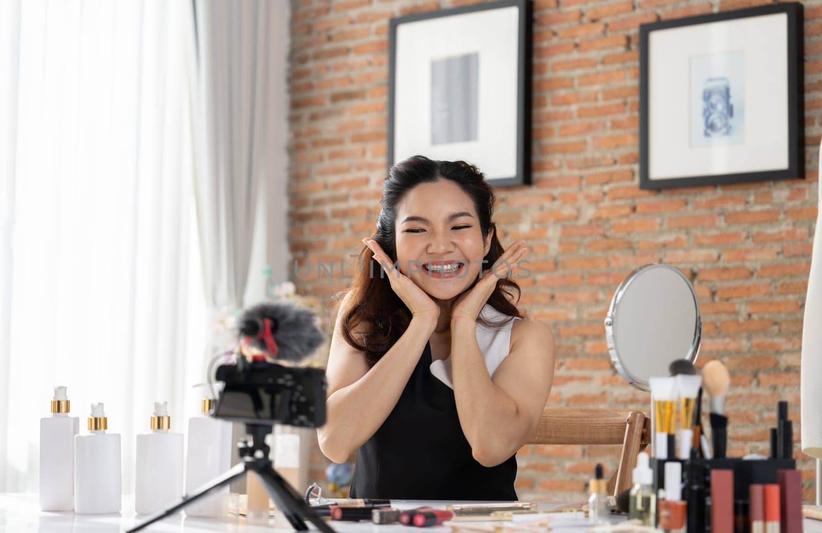 Asian Woman influencer shoot live streaming vlog video review makeup uttermost social media or blog. Happy young girl with cosmetics studio lighting for marketing recording session broadcasting online