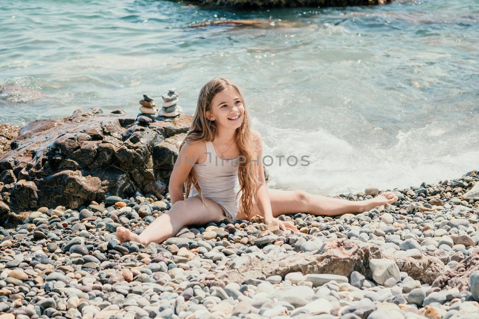 Woman and her daughter practicing balancing yoga pose on one leg up together on rock in the sea. Silhouette mother and daughter doing yoga at beach by panophotograph