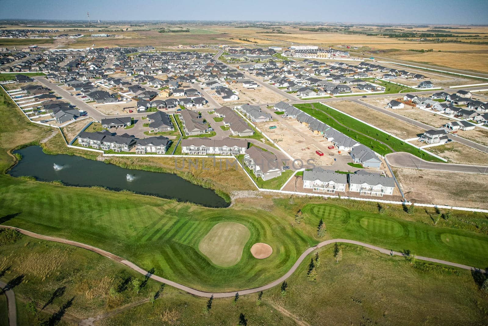 Drone image capturing the town of Warman in Saskatchewan during the summer season, highlighting its suburban and residential areas surrounded by lush greenery and vibrant atmosphere