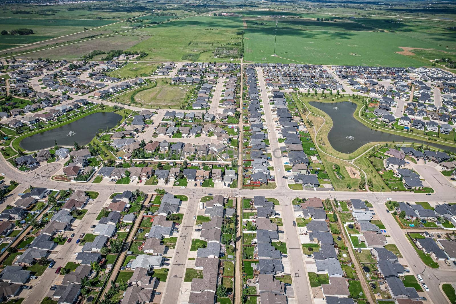 Drone image capturing the town of Warman in Saskatchewan during the summer season, highlighting its suburban and residential areas surrounded by lush greenery and vibrant atmosphere