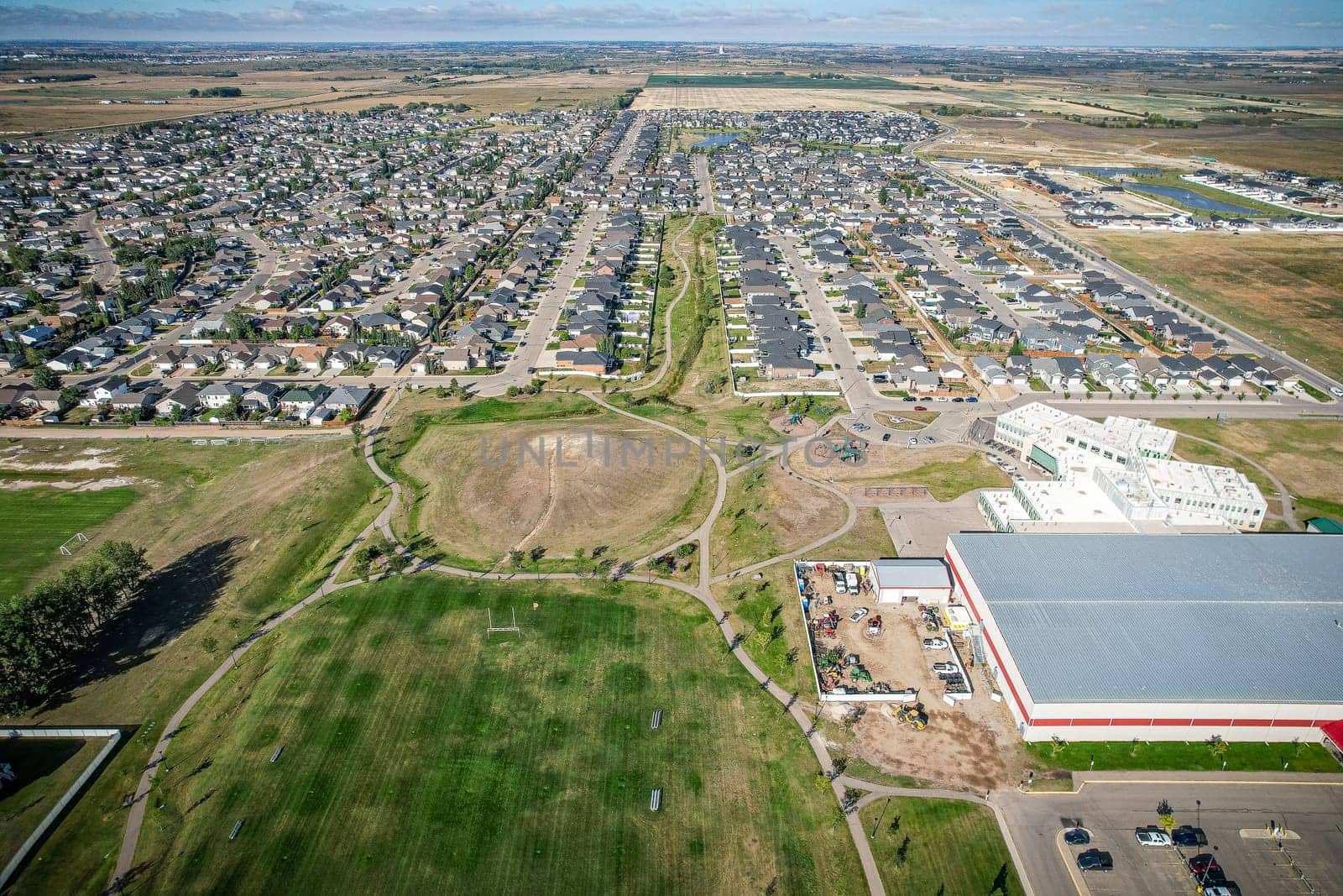 Drone image capturing the town of Warman in Saskatchewan during the summer season, highlighting its suburban and residential areas surrounded by lush greenery and vibrant atmosphere