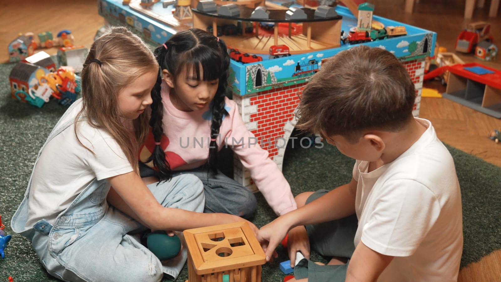 Top view of diverse students play wooden block together at playroom. Erudition. by biancoblue