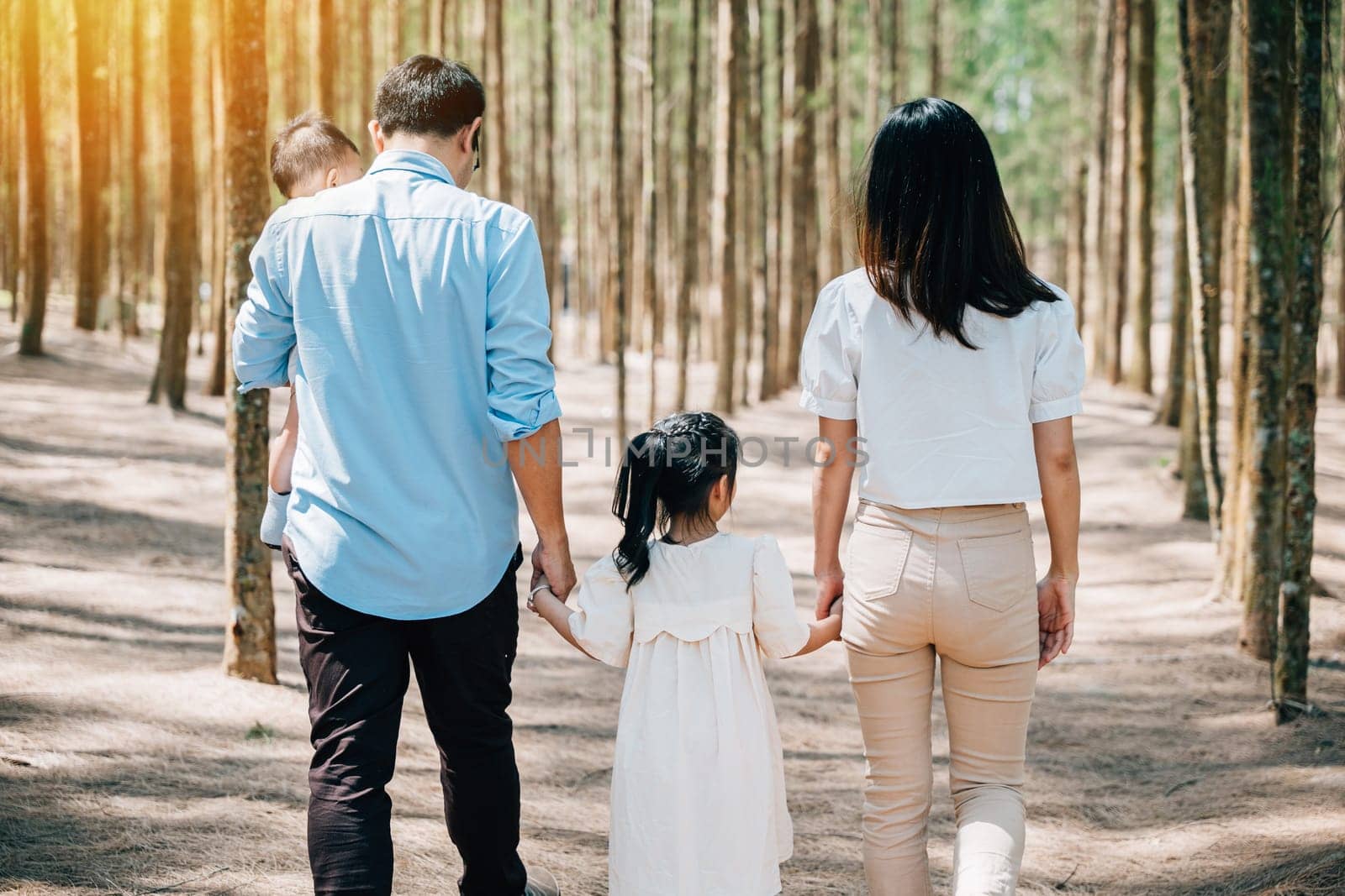 Happy family walking through the sunny forest by Sorapop