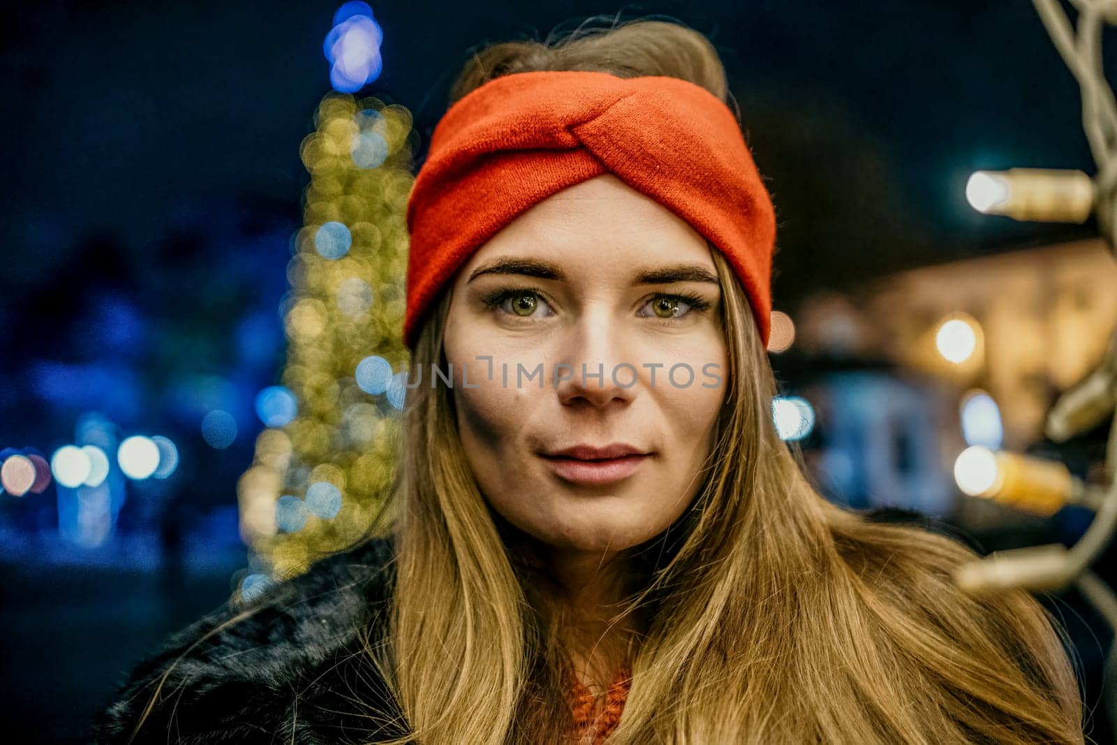happy smiling woman in a red hat stands on the street, holding light in her hands. Winter fun on the street: Christmas or New Year celebration. Slow motion by panophotograph