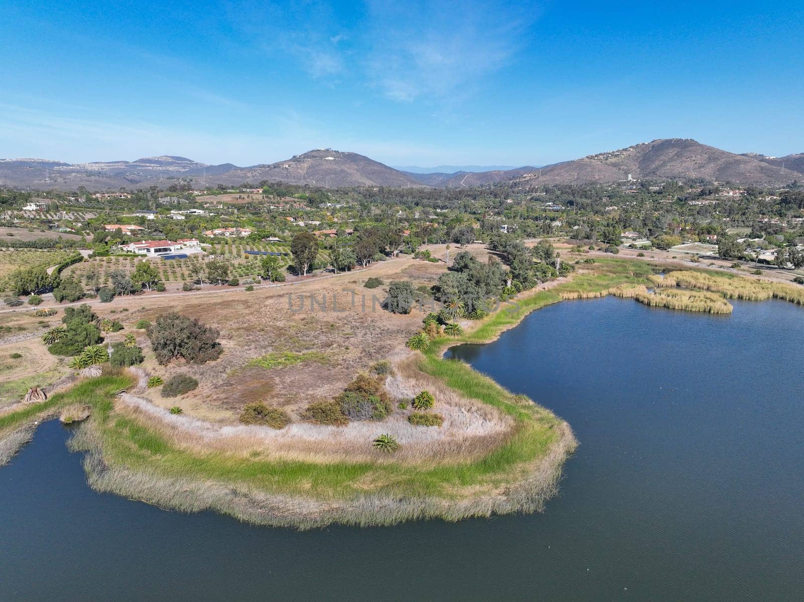 Aerial view over water reservoir and a large dam that holds water. Rancho Santa Fe in San Diego by Bonandbon