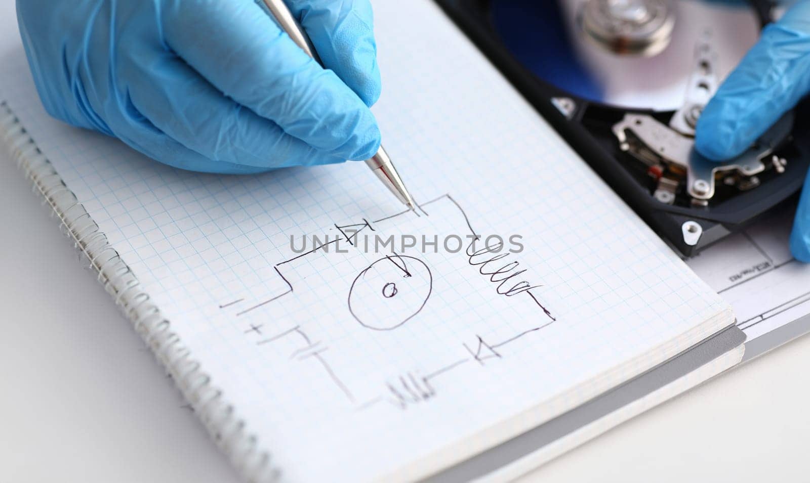 A male repairman in blue protective gloves examines an electrical printer's schematic of the hard disk unit that performs its diagnostics and repair