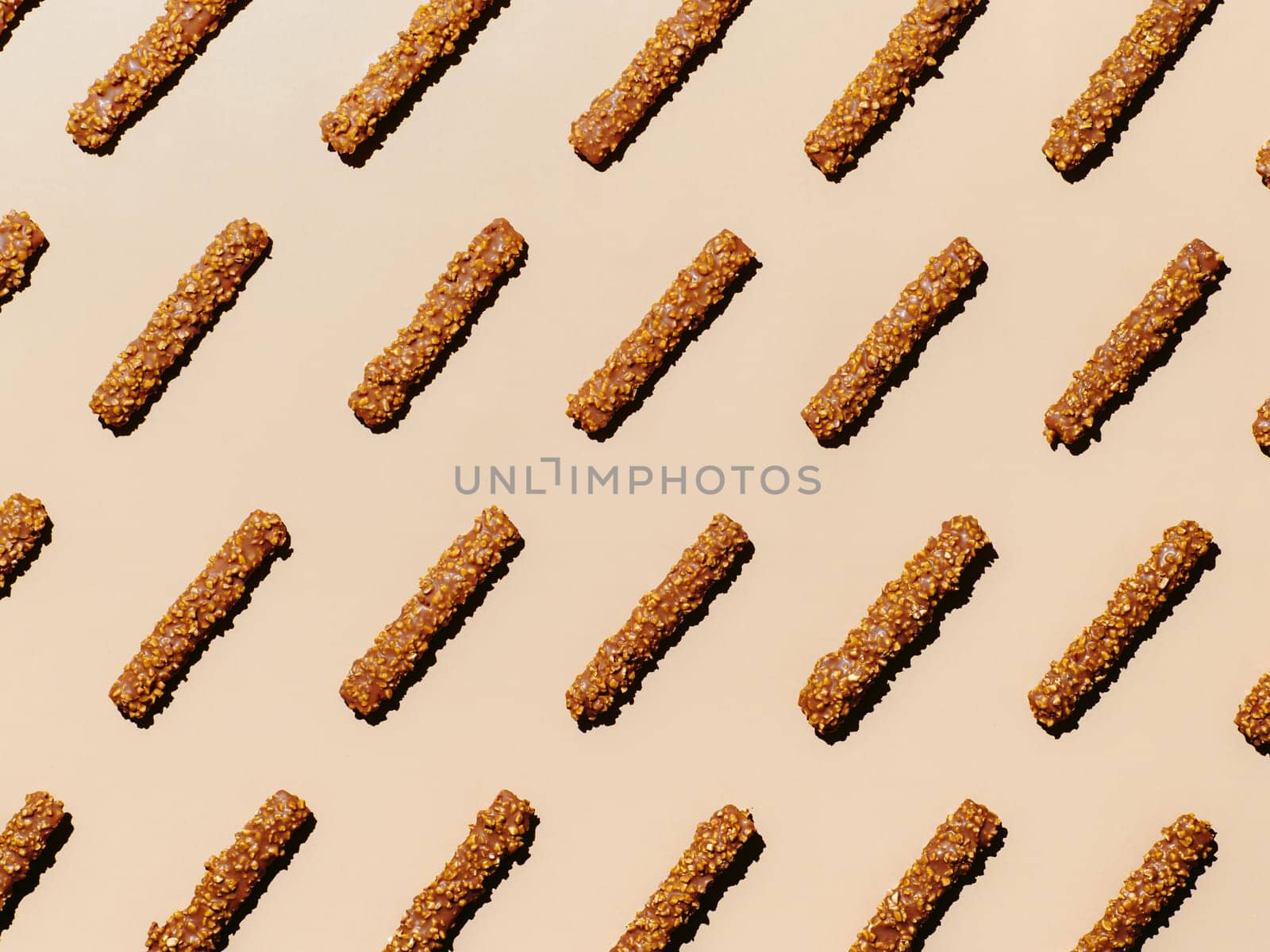 Chocolate candy with peanuts. Long sticks chocolate candy pattern on beige background. Sweet food pattern aesthetic. Food knolling