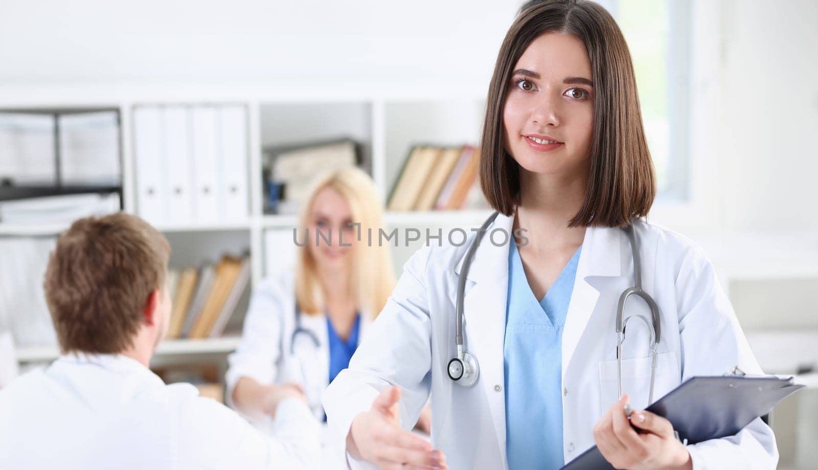 Female medicine doctor hold pad and give arm to shake in office closeup. Friend welcome introduction or thanks gesture test work examine patient congratulation help exam teamwork deal concept