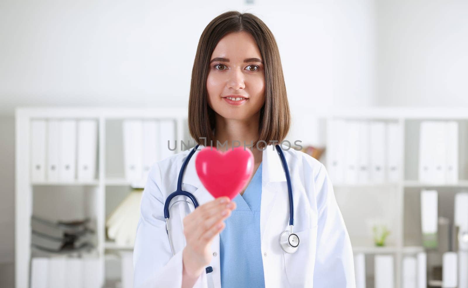 Female medicine doctor hands holding and covering red toy heart closeup. Cardio therapeutist student education physician make cardiac physical heart rate measure arrhythmia concept