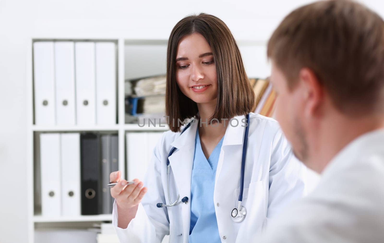 Beautiful smiling female doctor hold silver pen filling patient history list at clipboard pad. Physical exam er disease prevention ward round 911 prescribe remedy healthy lifestyle concept