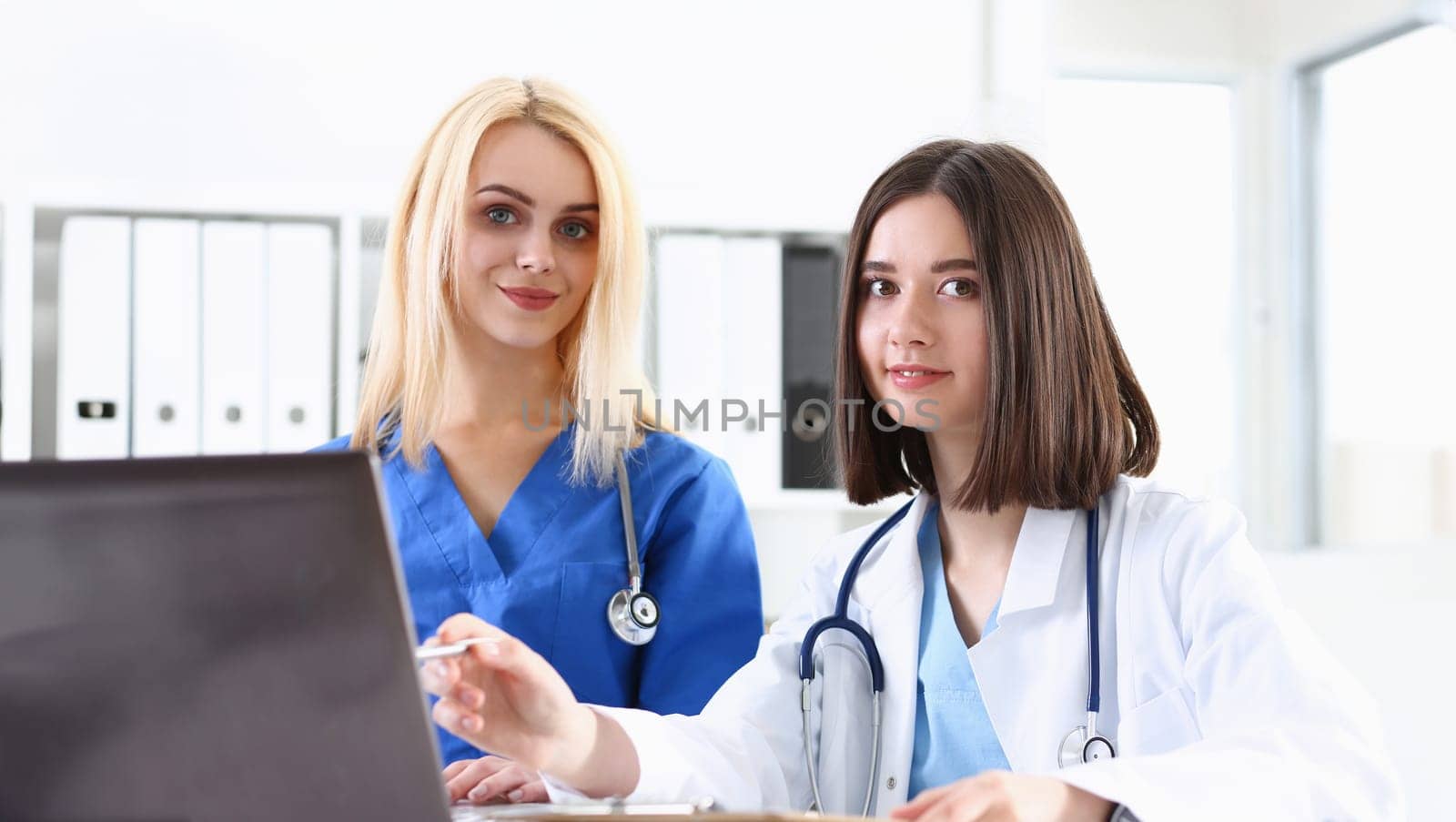 Group of doctors using laptop pc sitting in office. General practitioner portrait telemedicine therapeutist professional conversation modern communication remote cure expert assistance concept