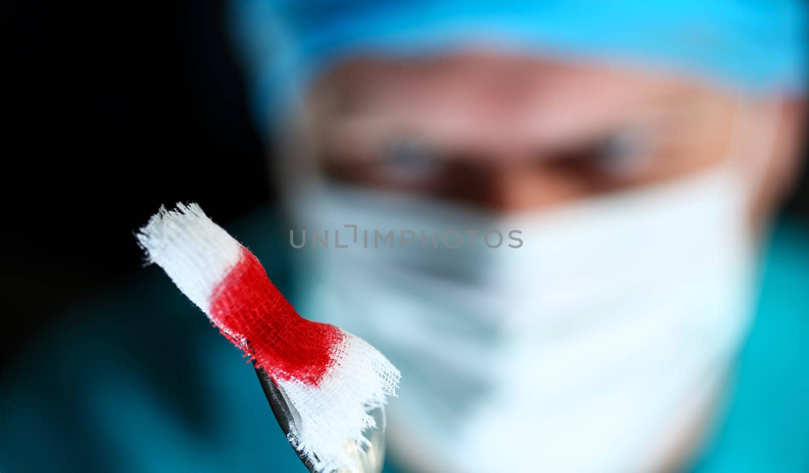 Surgeon in sterile uniform arms holding and passing to colleague tools with bio material wad closeup while operating patient. Stop bleeding put stitch er 911 concept
