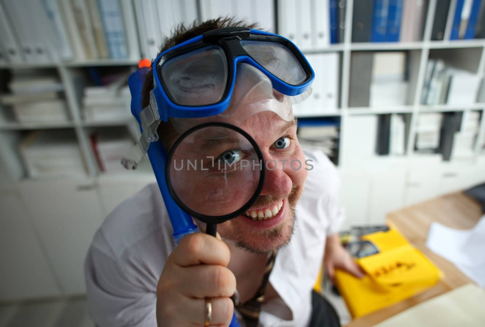 Funny smiling man wearing suit and tie in goggles and snorkel hold in arm magnifier glass at workplace in office portrait closeup. Searching data at online web about tourism 404 page error