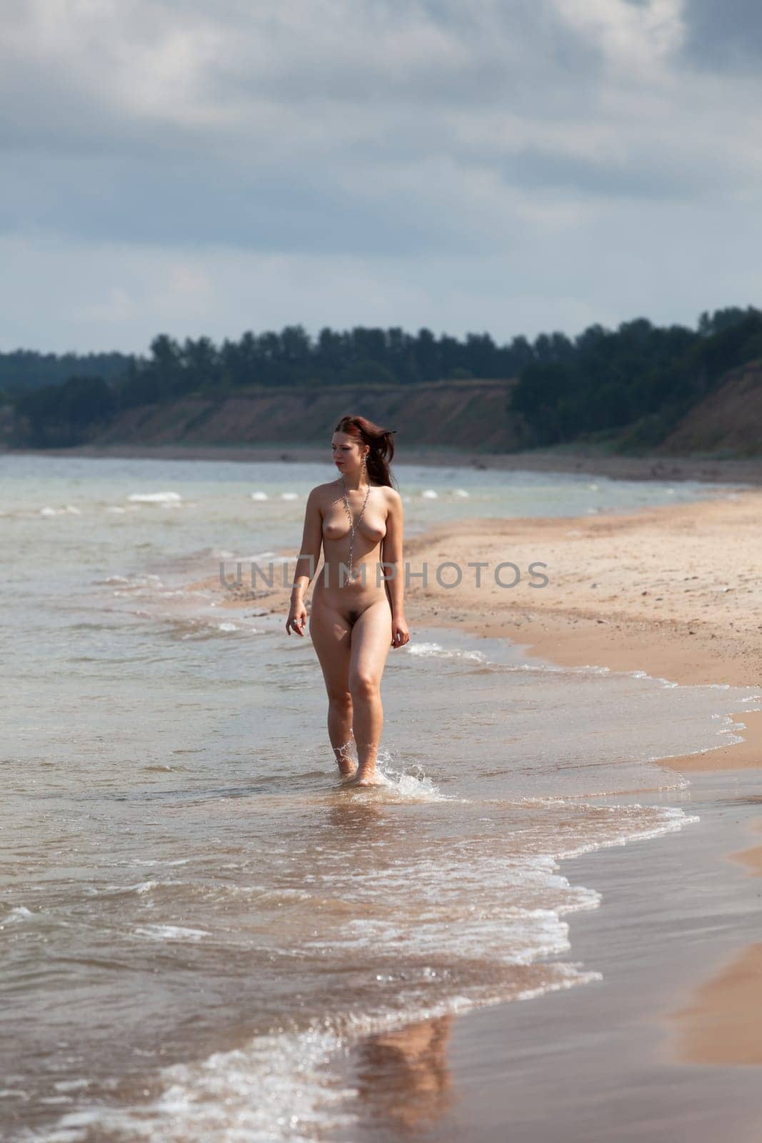 Beauty, nudity and healthy lifestyle. Young fully nude woman during a walk and jog in the morning on the seaside.