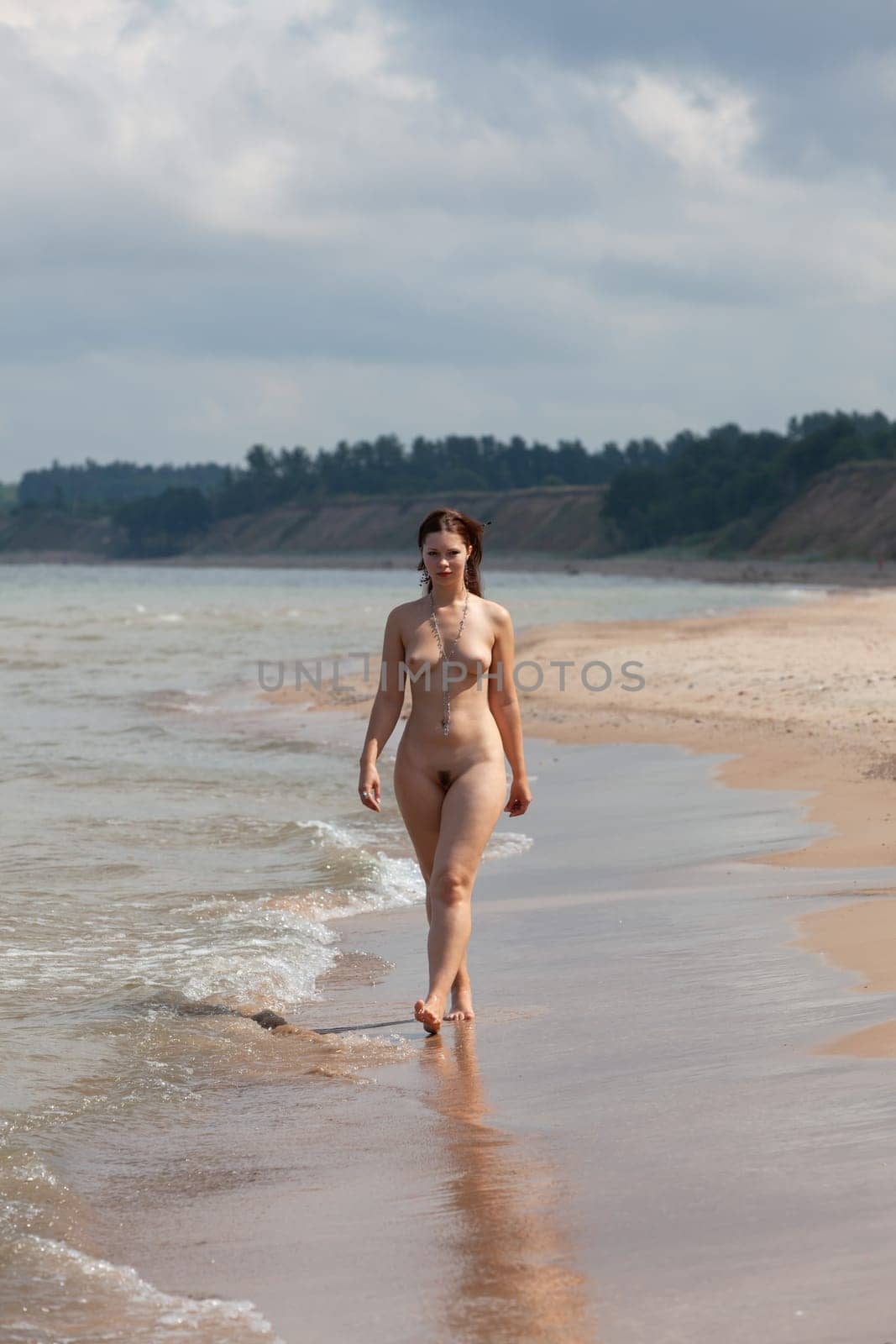 Beauty, nudity and healthy lifestyle. Young fully nude woman during a walk and jog in the morning on the seaside.
