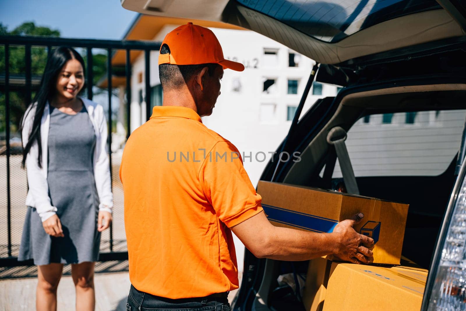 Emphasizing efficient home delivery service a courier in uniform hands a cardboard parcel to a smiling woman customer at her front house door highlighting modern delivery logistics.