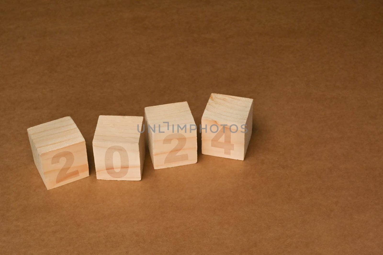 Wooden cube blocks with 2024 text on brown background. Start new year and business vision concept.