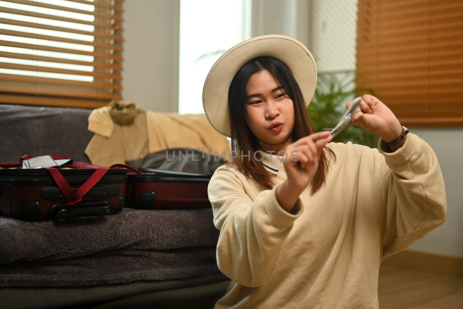 Cheerful young woman traveler in straw hat holding airplane model. Traveling, vacation and transportation concept.