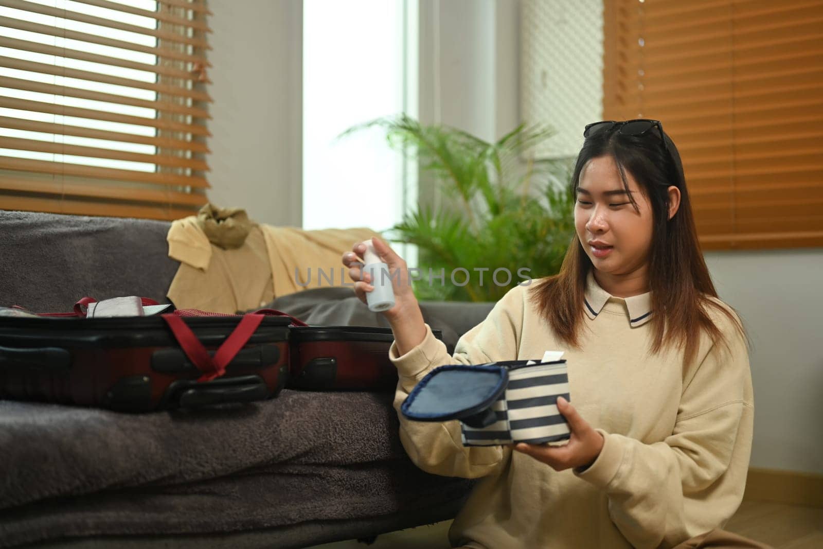 Happy young woman packing suitcase in living room getting ready for trip by prathanchorruangsak