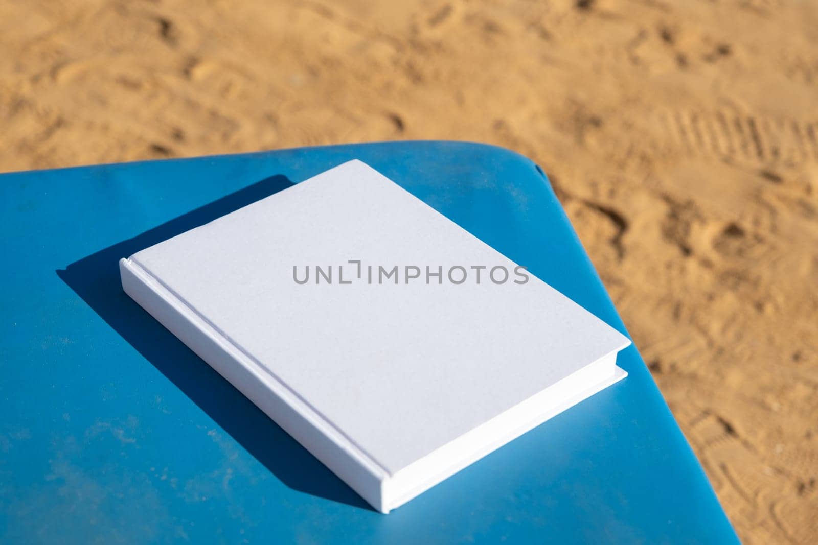 blank book mockup on lounge on sandy beach by Desperada