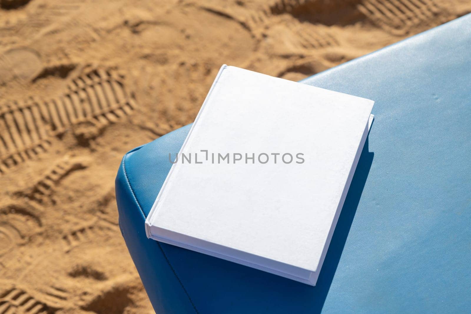 blank book mockup on lounge on sandy beach by Desperada