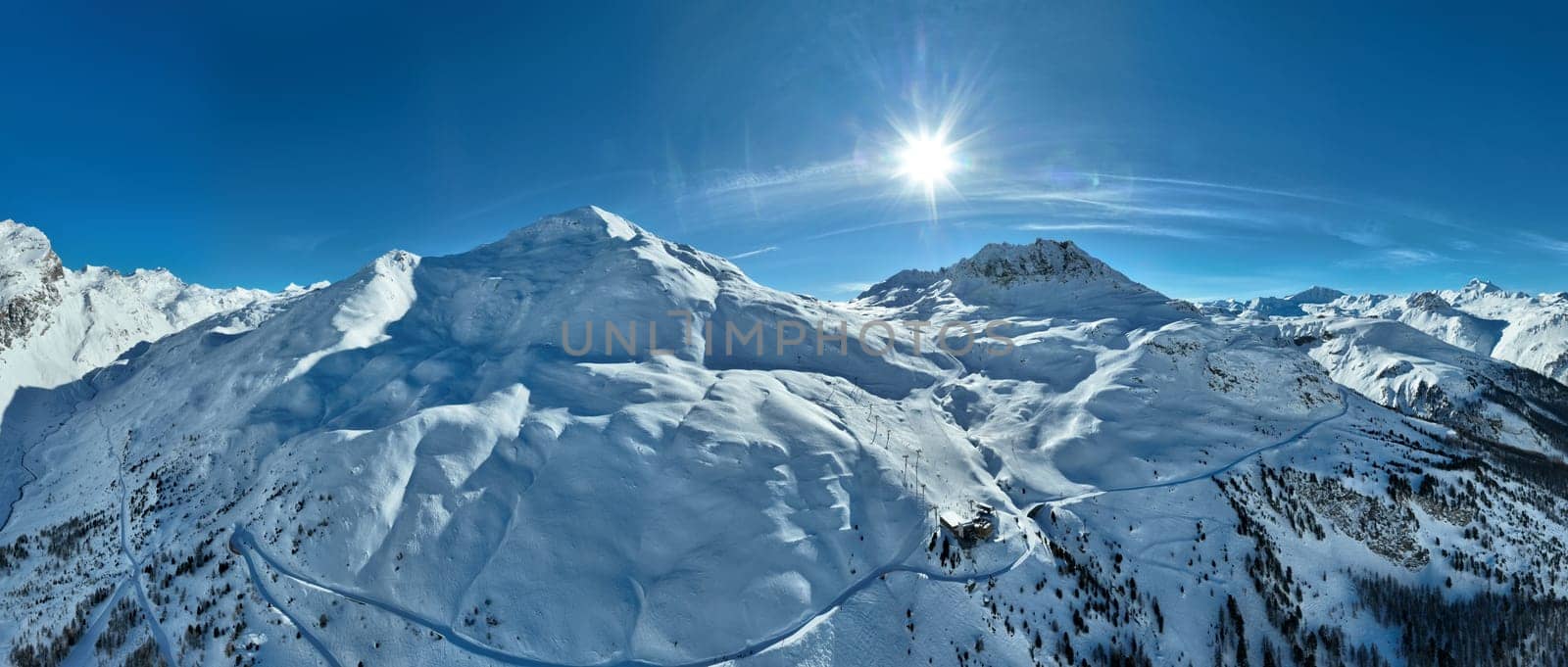 Winter drone shot of ski pistes and slopes covered with fresh powder snow in Tignes in Valdisere France. Alps aerial panoramic view on a beautiful sunny day ski lift snowboarding and skiing in resort