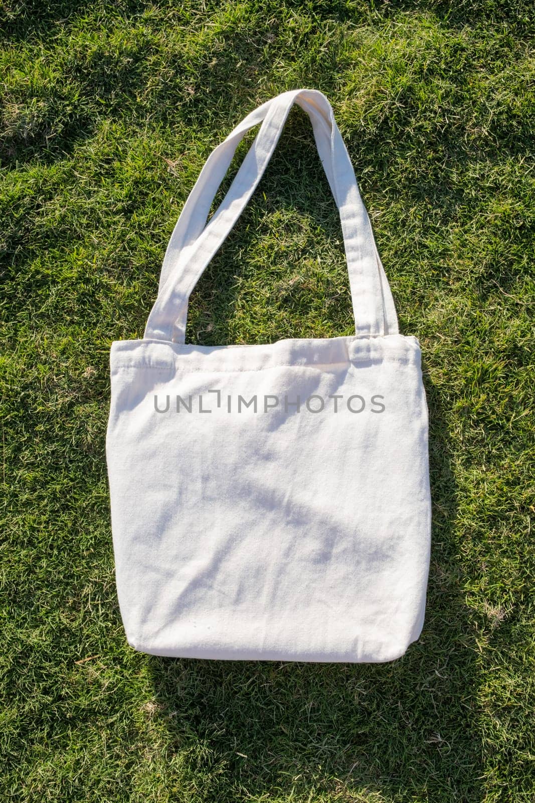 Mockup shopper handbag on green grass background. Top view copy space shopping eco reusable bag.