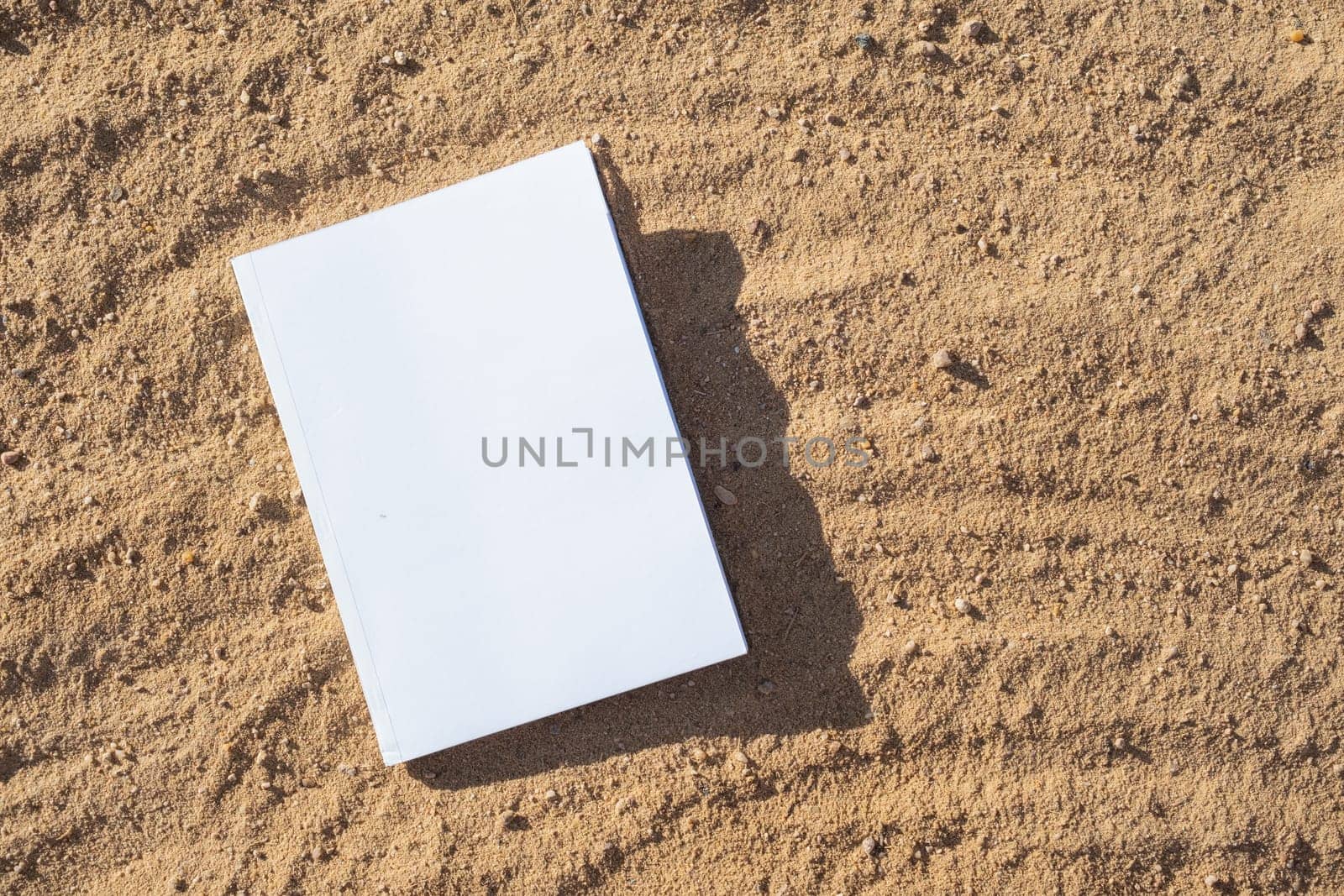 blank book mockup on sandy beach by Desperada