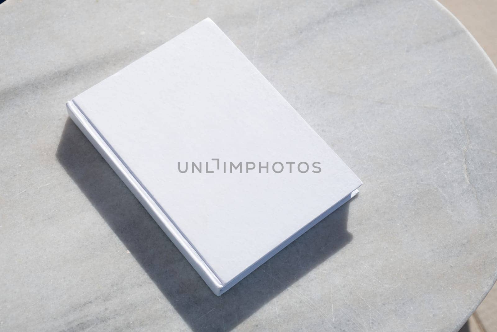 blank book for mockup design on marble table by the swimming pool by Desperada