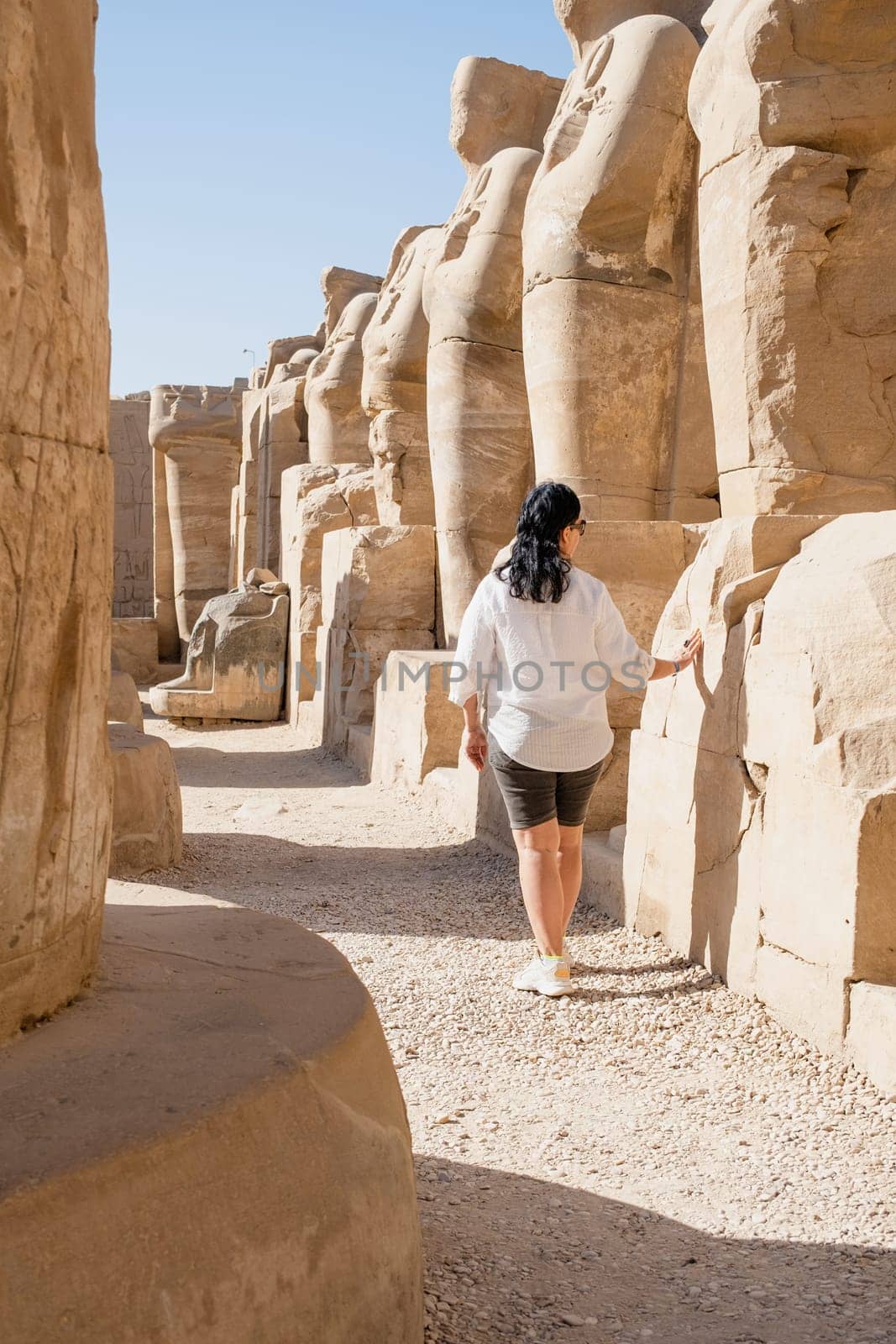 Woman traveler explores the ruins of the ancient Karnak temple in the city of Luxor in Egypt. by Desperada