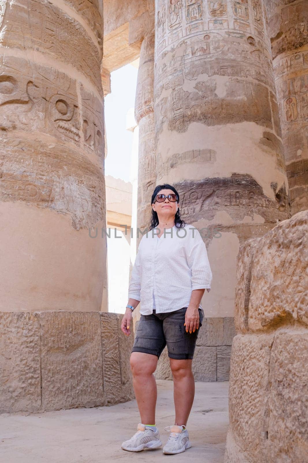 Woman traveler explores the ruins of the ancient Karnak temple in the city of Luxor in Egypt. by Desperada