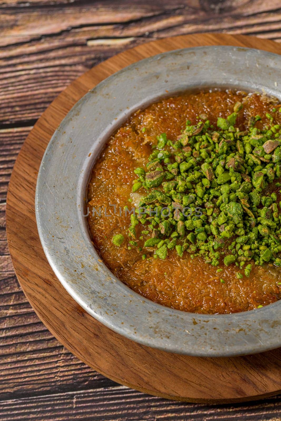 Traditional Turkish dessert pistachio kunefe on wooden table by Sonat