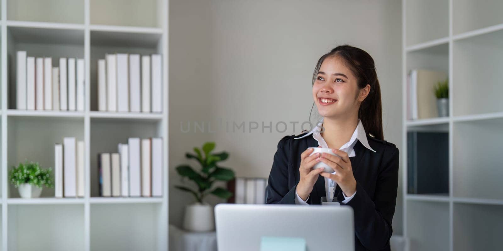 Portrait of happy and successful young Asian business woman employee in modern office.